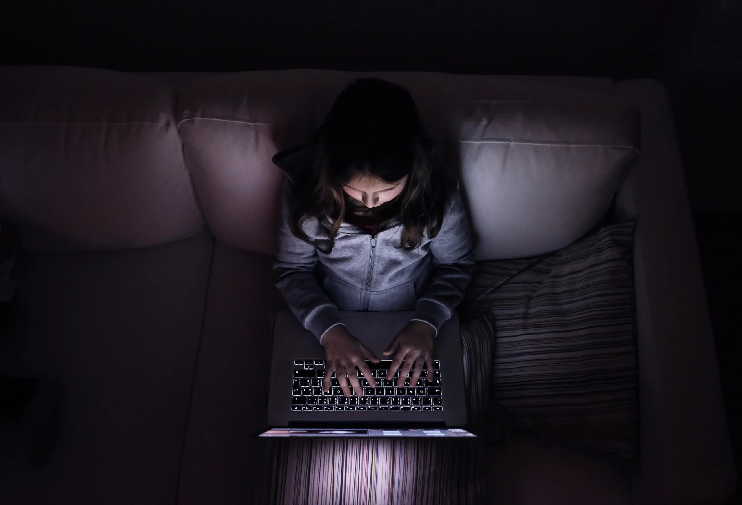 Little girl, sitting in a dark, playing with laptop