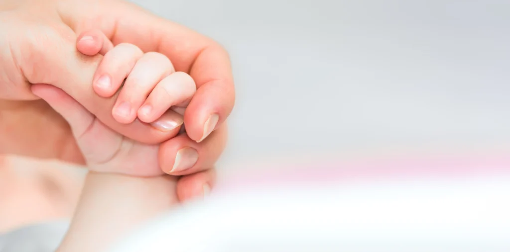 baby holding moms finger